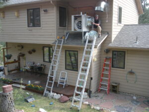 A man fixing an HVAC unit on the roof